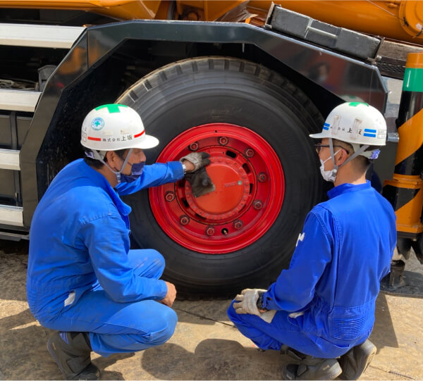 写真:新入社員が先輩にクレーンの整備点検方法を習っている様子